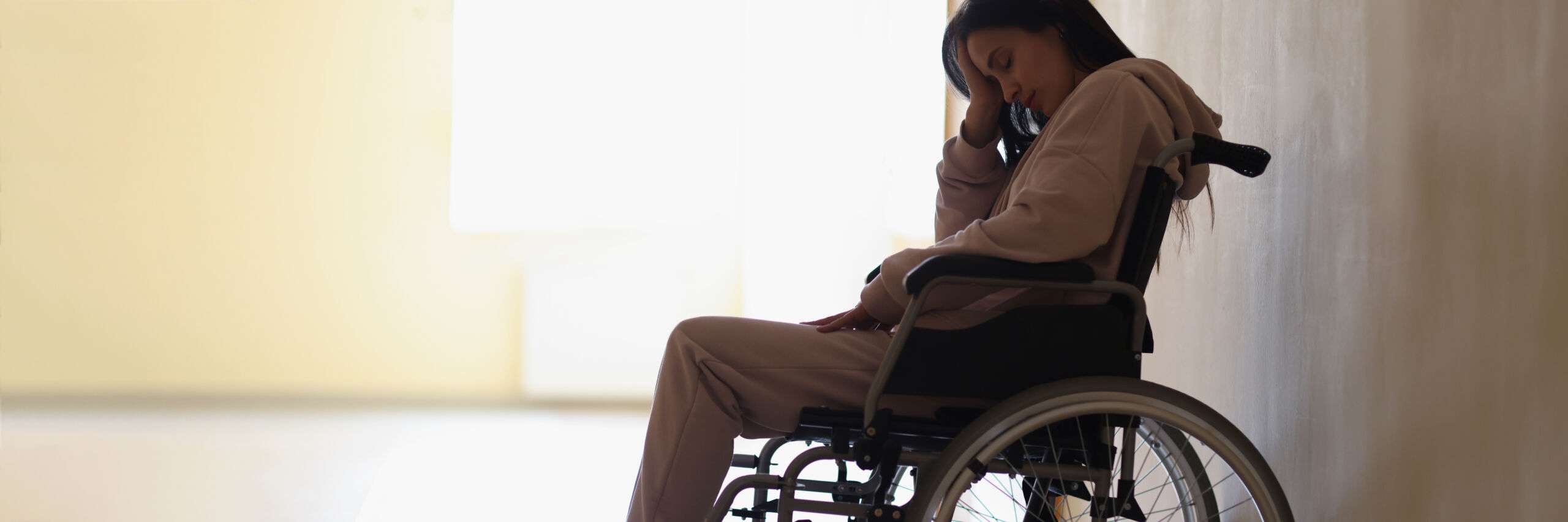 Sad woman sitting in wheelchair in rehabilitation center. Psychological assistance for people with disabilities concept